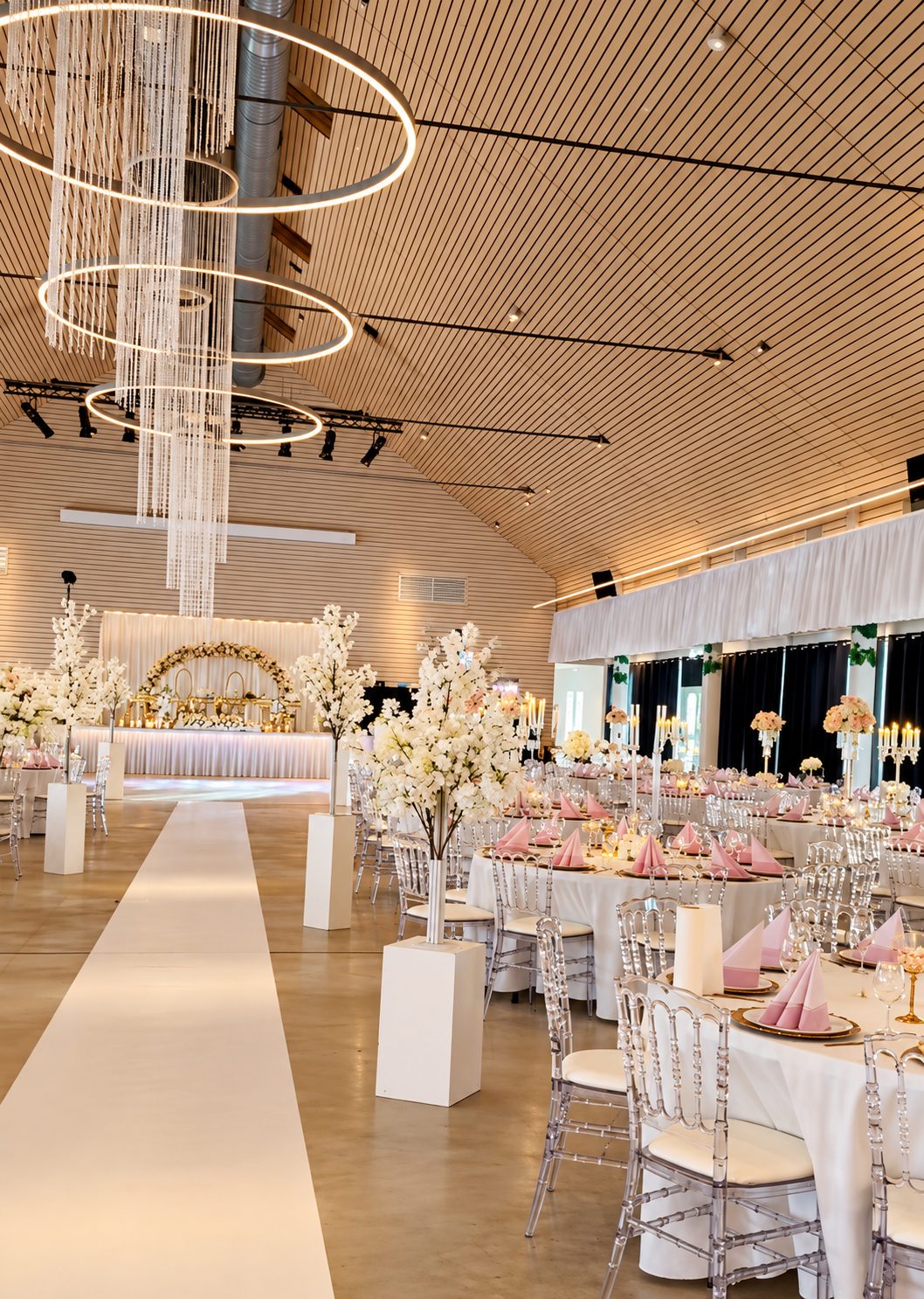 Salle de réception avec lustres, fleurs blanches et tables dressées